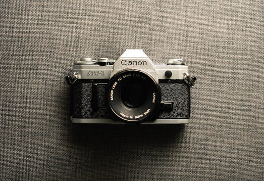 black and gray Canon camera on gray textile